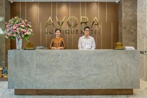 岘港AVORA Boutique Hotel的站在柜台后面的男人和女人