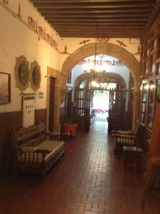 帕茨库卡罗Hotel Los Escudos的一座带长椅和拱门的走廊的建筑