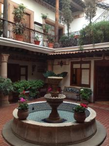 帕茨库卡罗Hotel Los Escudos的植物繁茂的建筑庭院中的喷泉