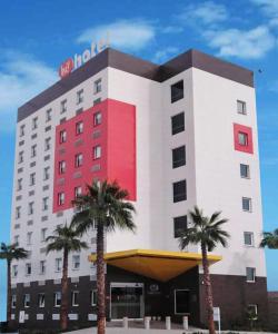 托雷翁Hotel Hi ! Torreon Aeropuerto-Galerías的一座酒店大楼前面有棕榈树