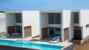 BelnemCARAIBAS Bonaire modern air-conditioned vacation home for architectural design lovers的一座带游泳池和两把蓝色椅子的建筑