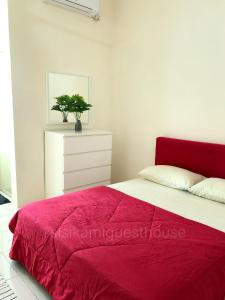 樟仑Sisikami Guesthouse的一间卧室配有红色的床和白色梳妆台
