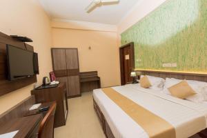德里久尔Kallada Golden Hotel的配有一张床和一台平面电视的酒店客房