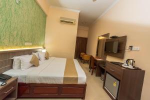 德里久尔Kallada Golden Hotel的酒店客房配有一张床、一张书桌和一台电视。