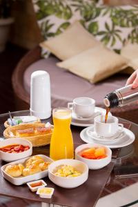 纳塔尔Status Motel的一张桌子,上面放着一盘早餐食品和橙汁