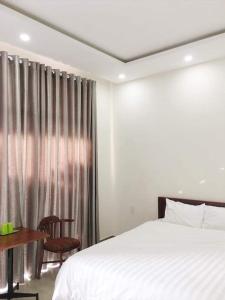 岘港Motel Thanh Long的一间卧室配有一张床、一张桌子和一个窗户。