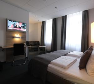科布伦茨Hotel Hohenstaufen的酒店客房设有一张床、一张书桌和一台电视机。