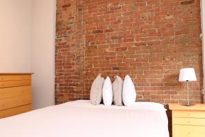 波士顿Furnished Studio in the South End #4的一间卧室设有砖墙和一张带枕头的床