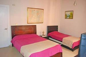 科韦尼亚斯亚特兰蒂斯民宿的卧室内的两张床,配有粉红色和白色床单