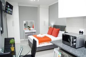 开普敦Cape Town Micro Apartments的一间卧室配有带橙色枕头和微波炉的床。