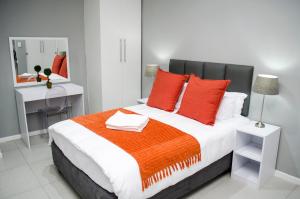 开普敦Cape Town Micro Apartments的一间卧室配有一张大床、红色枕头和镜子