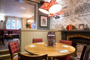 布罗姆利Toby Carvery Beckenham by Innkeeper's Collection的餐厅设有木桌、椅子和壁炉