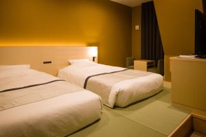 东京Tosei Hotel Cocone Ueno的酒店客房设有两张床和电视。