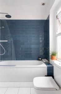 马伯斯Beautiful Two Bed Mumbles Flat - with parking space的浴室设有白色浴缸和蓝色瓷砖墙。