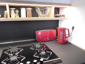 萨格勒布New cosy apartment near Arena的厨房柜台配有炉灶和红色用具