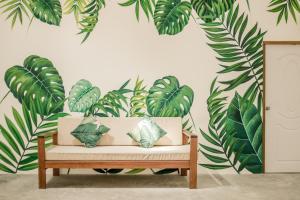奥南海滩Whalecome Aonang Resort-SHA Extra Plus的一张长着叶子壁画的房间的长凳