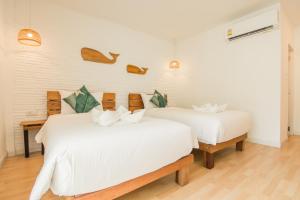 奥南海滩Whalecome Aonang Resort-SHA Extra Plus的配有白色墙壁和木地板的客房内的两张床