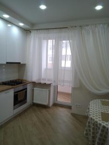 布恰Подобово апартаменти в м Буча的厨房配有白色窗帘和大窗户