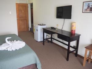 圣何塞纽沃马拉家托旅馆酒店的客房设有一张桌子、一台电视和一张床