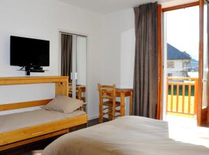 Aillon-le-JeuneHôtel du Soleil的一间卧室配有一张床、一台电视和一个阳台