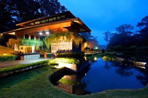 Quesada埃托卡诺温泉度假酒店的一座在晚上有池塘的建筑