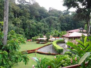 Quesada埃托卡诺温泉度假酒店的花园,花园中设有池塘和建筑,树木繁茂