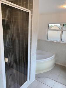 阿斯科特林德里克斯别墅酒店的带浴缸和玻璃淋浴间的浴室。