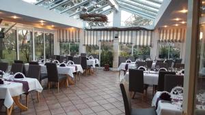 施塔德安可雅酒店的餐厅设有白色的桌椅和窗户。