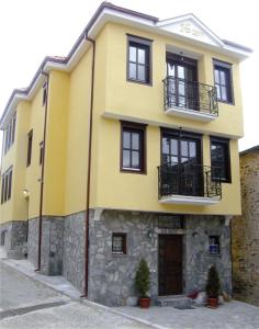 克鲁舍沃Casa La Kola Krusevo的黄色的房子,有黑色的窗户和石墙