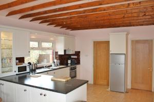 丁格尔Ard na Carraige, Ventry Holiday Home的厨房配有白色橱柜和木制天花板