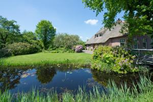 羊角村Giethoorn Lodge的一座老房子,前面有一个池塘