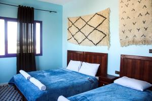 西迪考乌奇Dar Iziki的蓝色墙壁客房的两张床