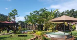 马六甲Fuga Village BeachGetaway的后院设有游泳池、遮阳伞和秋千