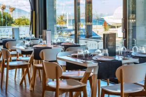 帕拉塔蒙Porto Marine Hotel的餐厅设有桌椅和大窗户。