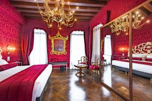 威尼斯Palazzo San Lorenzo的红色卧室设有两张床和吊灯。