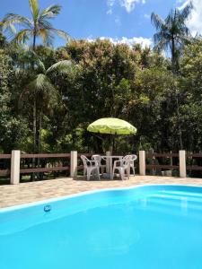 莫雷蒂斯Pousada Serra Verde Ecolodges的游泳池旁配有遮阳伞的桌椅