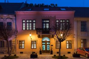 奥西耶克Boutique hotel Tvrđa的粉红色和黄色的建筑,晚上有门