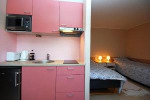 Nasva毕布图素度假屋的一间带粉红色橱柜和一张床的小厨房