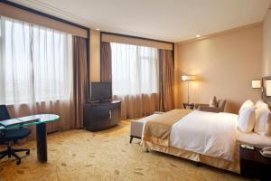 牡丹江牡丹江世茂假日酒店的酒店客房配有一张床、一张书桌和一台电视。