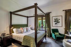 阿德莱德Mount Lofty House & Estate Adelaide Hills的一间卧室配有天蓬床和绿椅