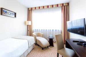 罗兹罗兹Qubus酒店的酒店客房配有一张床、一张书桌和一台电视。