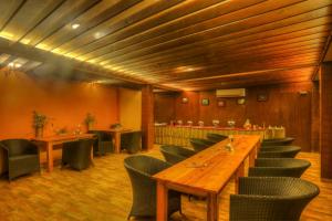 卡纳塔尔The Hermitage Kanatal的餐厅设有长木桌子和椅子