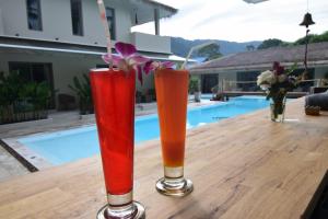 拉迈AMAYA Resort的三个鸡尾酒坐在泳池旁的木桌旁