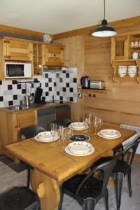 莱孔塔米讷蒙茹瓦L'Enclave的厨房配有带盘子和玻璃杯的木桌