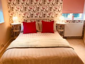 格雷夫森德Wisteria Cottage的一间卧室配有一张大床和两个红色枕头