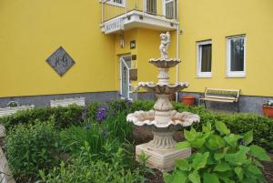 达姆施塔特加尔达酒店&餐厅的花园中的喷泉,位于黄色建筑前