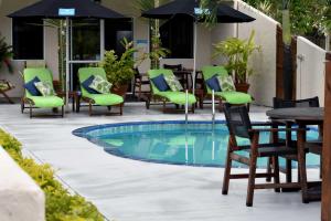 拉罗汤加珊瑚金沙公寓酒店的一个带桌椅和遮阳伞的游泳池
