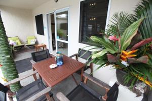 拉罗汤加珊瑚金沙公寓酒店的种植了植物的门廊上的木桌和椅子