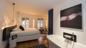 里昂MiHotel Vieux Lyon的一间卧室配有一张床、一个浴缸和一台电视。