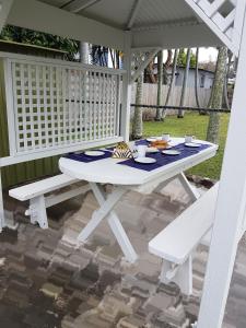 布里斯班Holiday House的庭院里设有一张白色野餐桌和两个白色长凳